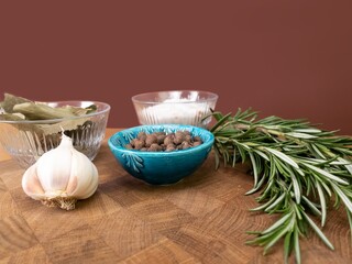 Still life with spices for meat: rosemary, garlic, pepper, salt. Photo with depth of field blur. Spices on a beautiful dark brown wooden board. Selection of spices herbs. Side view 