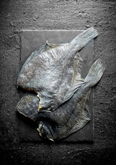 Raw fish on a black stone Board.