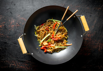 Fragrant Chinese cellophane noodles in a frying pan wok with salmon and vegetables.