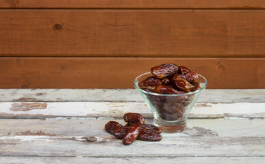 Glass bowl of dried dates on aged wooden table.