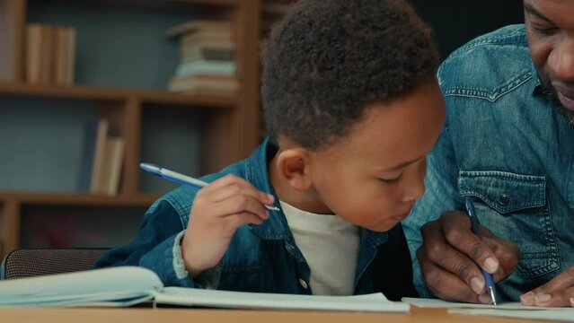 African American Child Boy With Ethnic Father Learning At Home. Dad Teacher Helping Little Son Pupil Preparing For Test Primary School Kid Doing Homework With Daddy Man Writing Task Distant Education