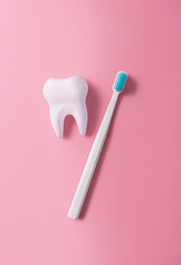 A plastic toothbrush next to a big tooth on a pink background. Oral hygiene. Flat lay, top view.