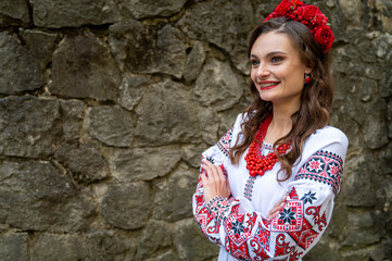 Portrait of a beautiful Slavic girl with long blond hair and blue eyes with a flower crown in a white and red embroidered dress with a bouquet. Traditional clothes of the Ukrainian