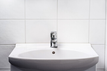 Bathroom sink. Toilet faucet, water tap and WC basin. Public, home or hotel room restroom interior design. Light and clean. Washing hands in washroom concept. Family apartment. White tile wall.