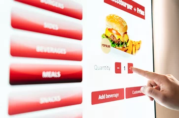 Deurstickers Self service order kiosk and digital menu in fast food burger restaurant. Touch screen in vending machine. Man using electronic selfservice technology and buying meal and paying. © terovesalainen