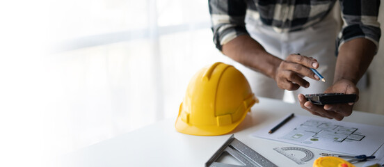 Engineer drawing a blue print design building or house, An engineer workplace with blueprints, pencil, protractor and safety helmet, Industry concept, copy space.