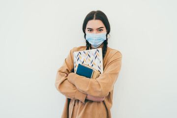 Young student in a protective mask with books