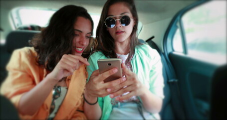 Friends in backseat of taxi car using smartphone. Millennials holding cellphone