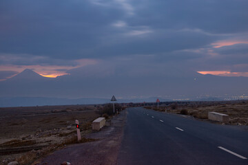 Asphalt road against backdrop of dramatic cloudy colorful sunset on a winter day