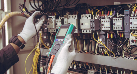 Electrician engineer tests electrical installations and wires on relay protection system.