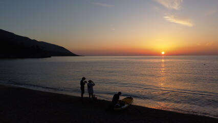 Fototapeta premium Three people on the beach meet the sunset