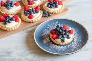 Vanilla custard tarts topped with raspberries and blueberries.
