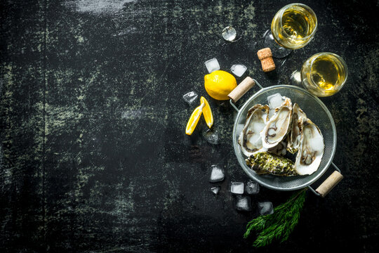 Opened oysters in a colander with white wine, lemon slices and ice cubes.