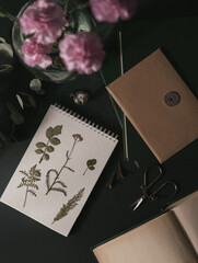 Vintage styled flat lay with pressed plants and books, dark academia and botanical aesthetic