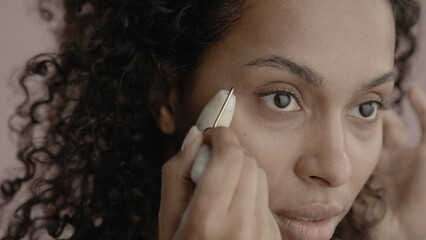 CU Headshot portrait of beautiful 20s African-American Black female cosmetic face roller against...