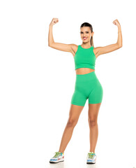 young sporty smiling woman in green shorts and top showing biceps on white background