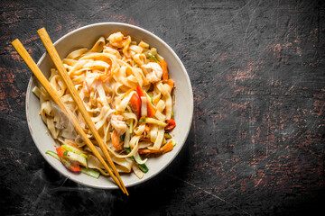 Hot noodles in a bowl with chopsticks.