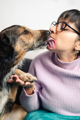 Dog kissing and giving paw to his owner, a Latin American woman. Vertical photography