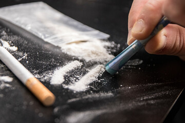 Drug Addiction: Close-up of person using a 20 euro note to snort cocaine on a black table