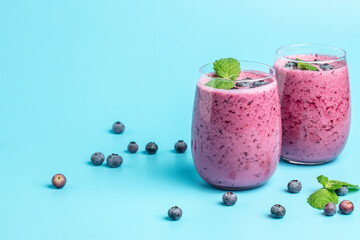 blueberry smoothie in glass on a blue background. Delicious balanced food concept