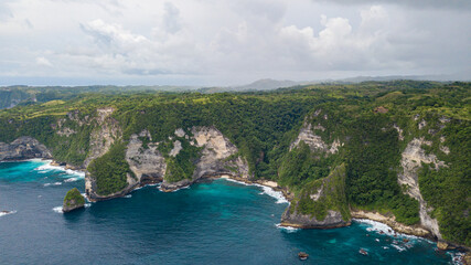 Beautiful coastline aerial view from Saren Cliff Point. Clear water and rocks with cloudy sky. Nusa Penida, Indonesia.