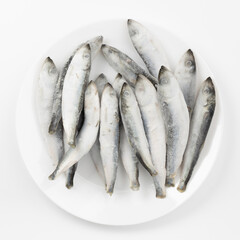 Raw sea frozen fish on a white plate.