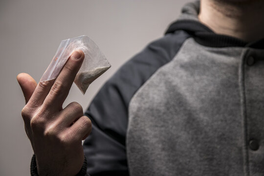 Mysterious faceless drug dealer holding a bag of cocaine or heroin. Concept of drug dealing or addiction