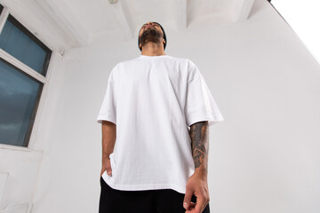 Stylish african american man in a white t-shirt stands in the studio on a white background.