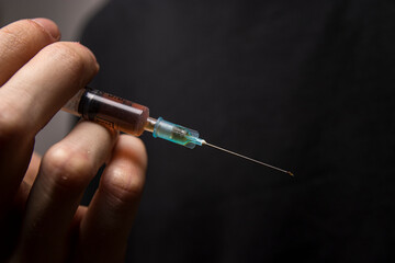 Close-up of a hand holding a heroin syringe. Drug addiction concept