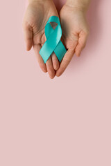Woman holding Teal ribbon. Symbolic for cervical cancer, ovarian cancer, gynecological cancer and PCOS. And sexual assault awareness.