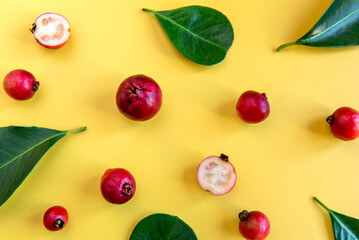 Leafs and Fruits Cattley guava, red fruit Psidium cattleyanum on yellow background.