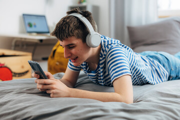 Young adolescent boy is listening to music using headphones