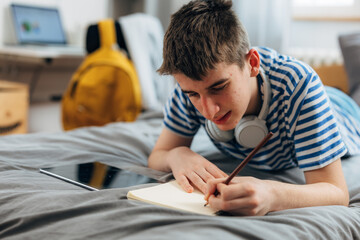 Teenage boy is doing his homework at home