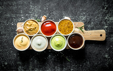 Sauces on a wooden cutting Board with garlic and rosemary.