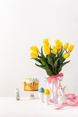 Festive interior, yellow tulips in a vase and Easter eggs, cute bunnies and Easter cake