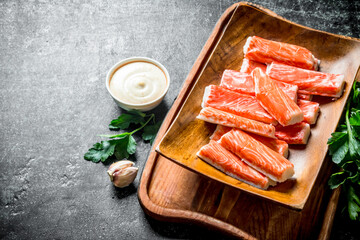 Crab sticks plate with garlic cloves, sauce and parsley.