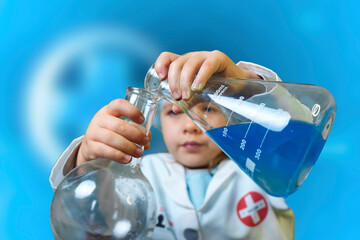 Little kid doing experiments with blue liquid. Cute child wants to become a doctor. Pretty child in...