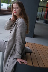 Business women in the elegant classic grey jacket is sitting on a bench. City style portrait of the girl