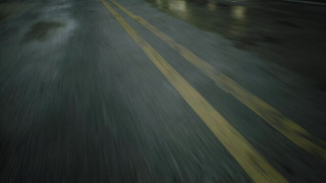 close-up cinematic POV shot of wet asphalt in the morning after rain on street road. Car or motorcycle is driving on the highway after rain