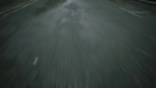 close-up cinematic POV shot of wet asphalt in the morning after rain on street road. Car or motorcycle is driving on the highway after rain