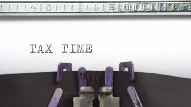 Tax time phrase closeup being typing and centered on a sheet of paper on old vintage typewriter mechanical