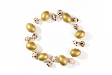 Eggs painted golden and quail eggs on white background. Minimal Easter concept.  Natural farm products. Round frame with place for text