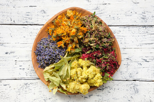 Wooden plate of medicinal herbs - lavender, calendula, red clover, helichrysum, lime tree flowers - ingredients for making of herbal medicine drugs, tea or infusion. Alternative herbal medicine.