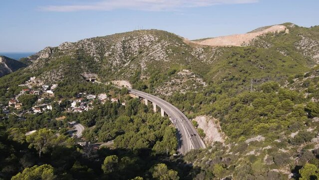 Drone view of highway crossing mountains and blue sea on clear horizon