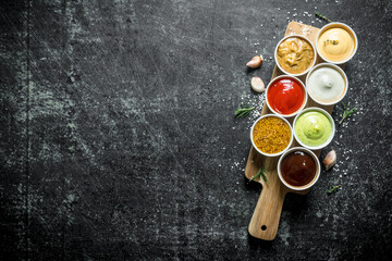 Different sauces in the bowls on the cutting Board.