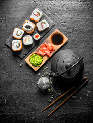 Pieces of delicious Japanese sushi rolls with green tea and sauces.