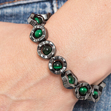 Pulseira de olho de tigre verde e hematita no pulso de mulher.