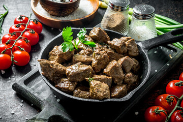 Fried liver with spices and cherry tomatoes on a cutting Board.