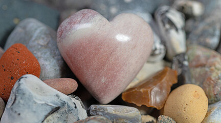 Herz aus Speckstein zwischen bunten Steinen