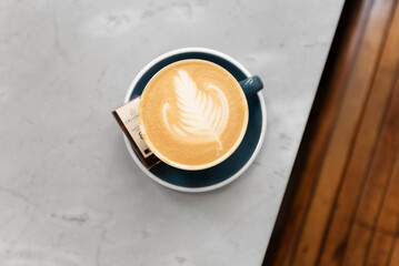 Close-up cappuccino with rosetta shape latte art on marble table at cafe, food and drink concept.